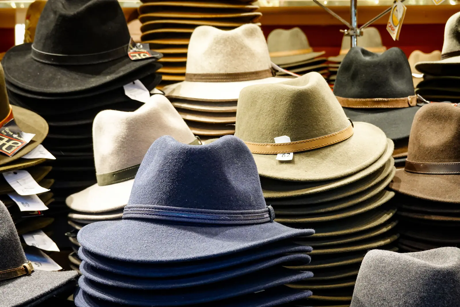 Stacks of felt hats in navy, olive, cream and brown on a shop table.